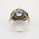 Antiker Goldring mit geschnitztem Band und großem facettiertem blauem Edelstein auf weißem Hintergrund