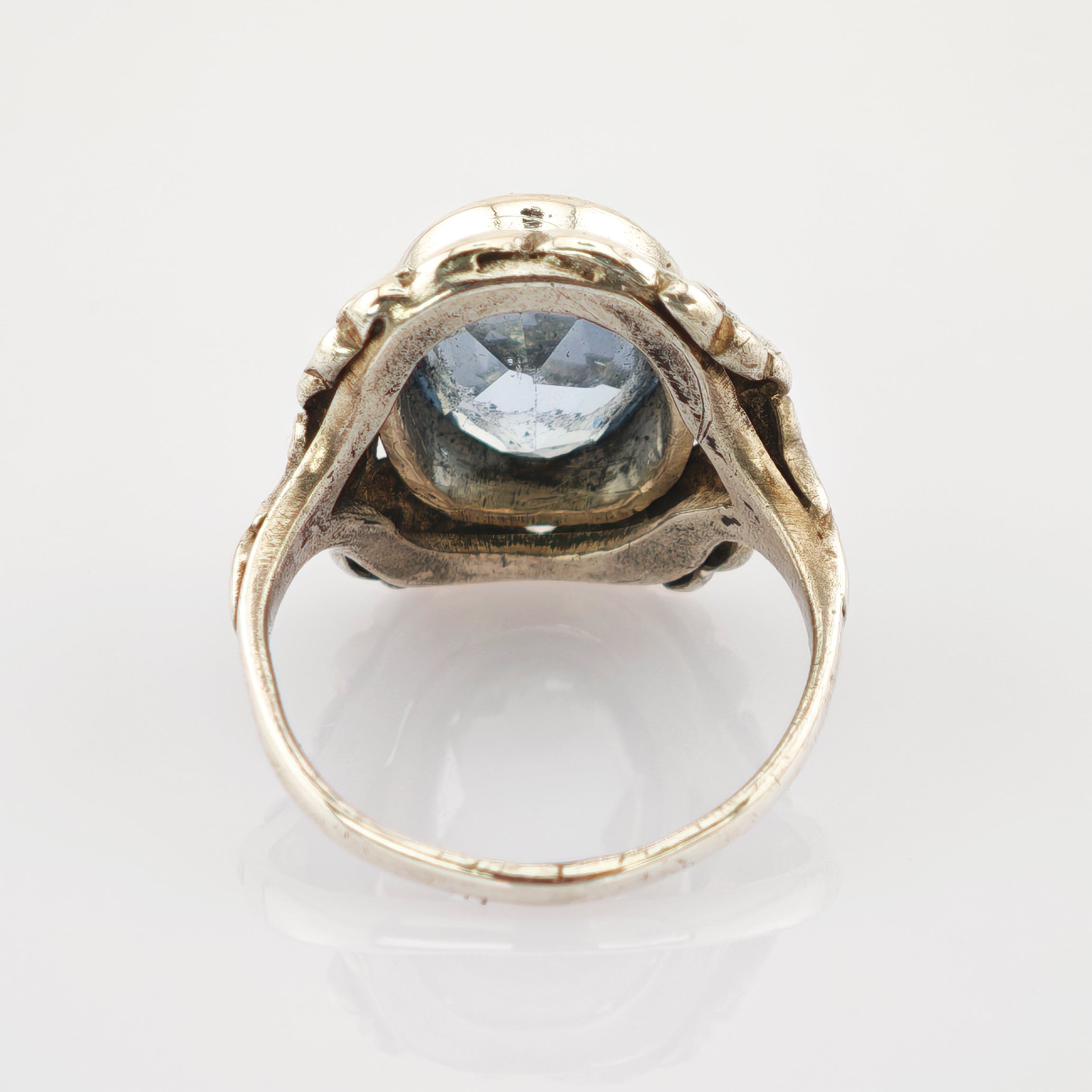 Antiker Goldring mit geschnitztem Band und großem facettiertem blauem Edelstein auf weißem Hintergrund