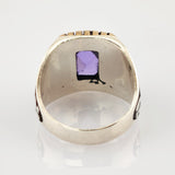 Nahaufnahme eines antiken Metallrings mit Innenprägung '906M' und violettem quadratischem Schmuckstück