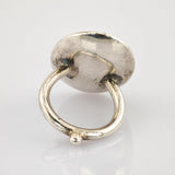 Antiker Metallring mit kreisförmiger Basis und sichtbaren Gebrauchsspuren auf spiegelnder Oberfläche.