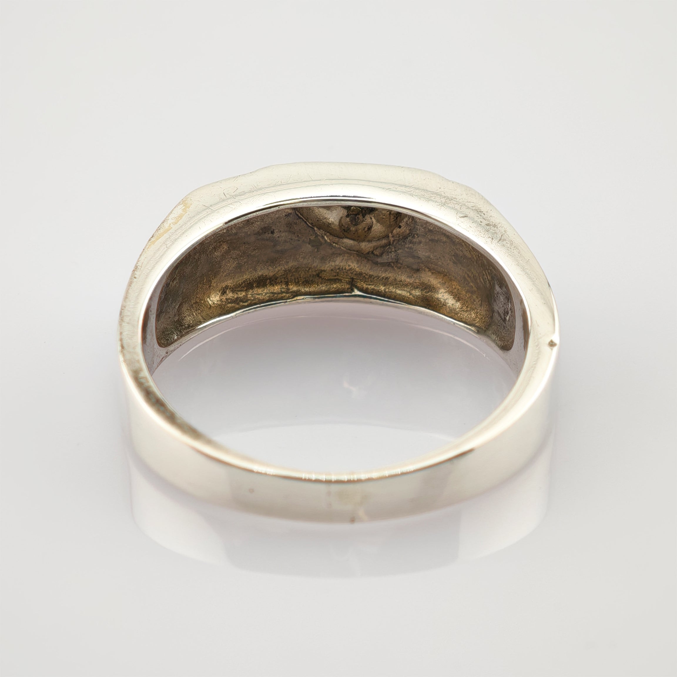 Antiker silberner Ring mit glatter, leicht angelaufener Innenseite und unregelmäßiger äußerer Form auf weißem Hintergrund.