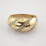 Breiter Goldring mit drei diagonalen Reihen funkelnder Diamanten auf weißem Hintergrund