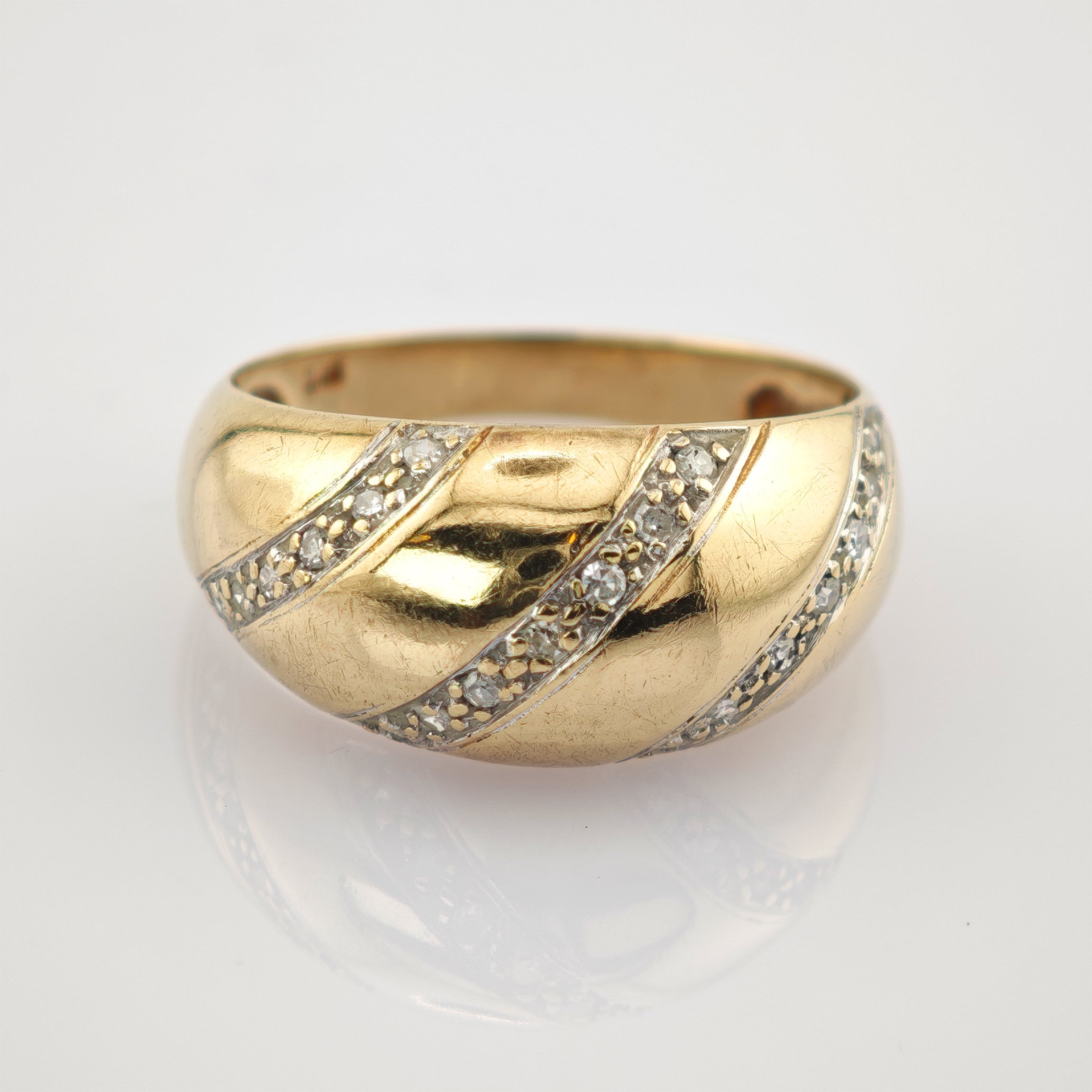 Breiter Goldring mit drei diagonalen Reihen funkelnder Diamanten auf weißem Hintergrund