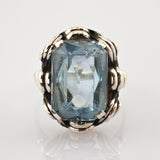 Dekorativer Ring mit rechteckigem blauem Edelstein und silberfarbenem Band im Vintage-Stil.
