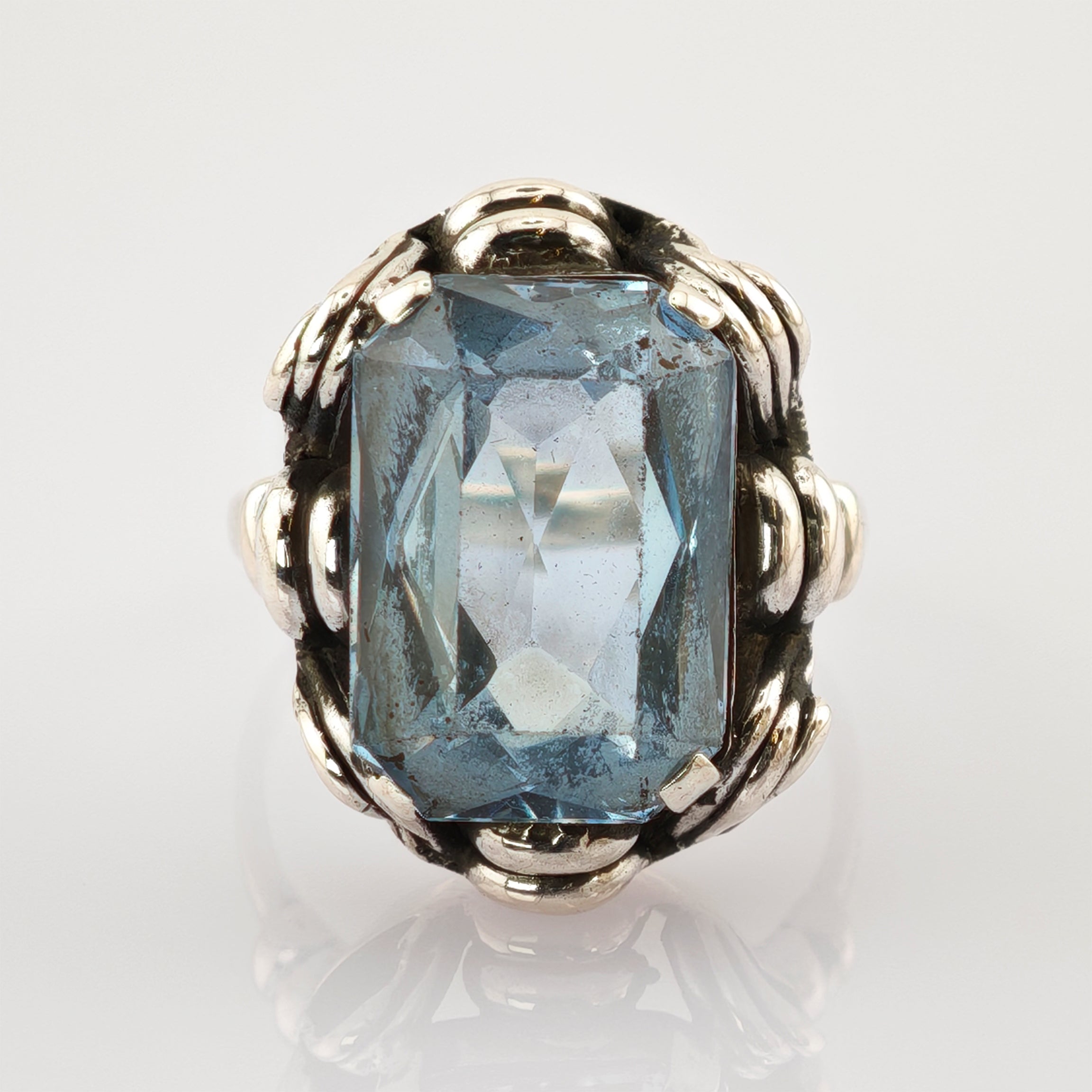 Dekorativer Ring mit rechteckigem blauem Edelstein und silberfarbenem Band im Vintage-Stil.