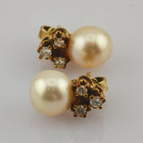 Elegante goldene Ohrringe mit großen cremefarbenen Perlen und drei kleinen klaren Edelsteinen.