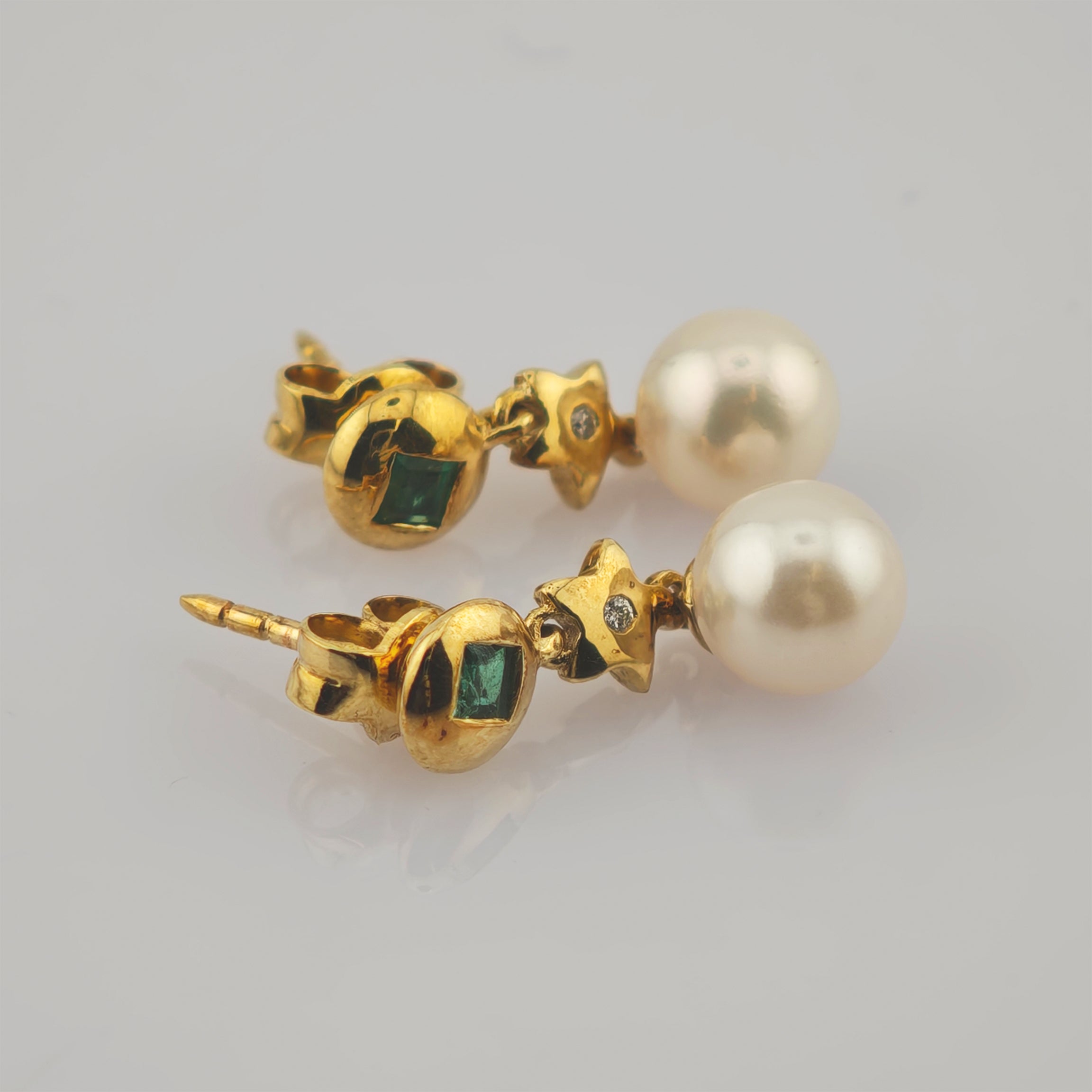 Elegante goldene Ohrringe mit runden Perlen, goldenen Sternen und grünen Edelsteinen