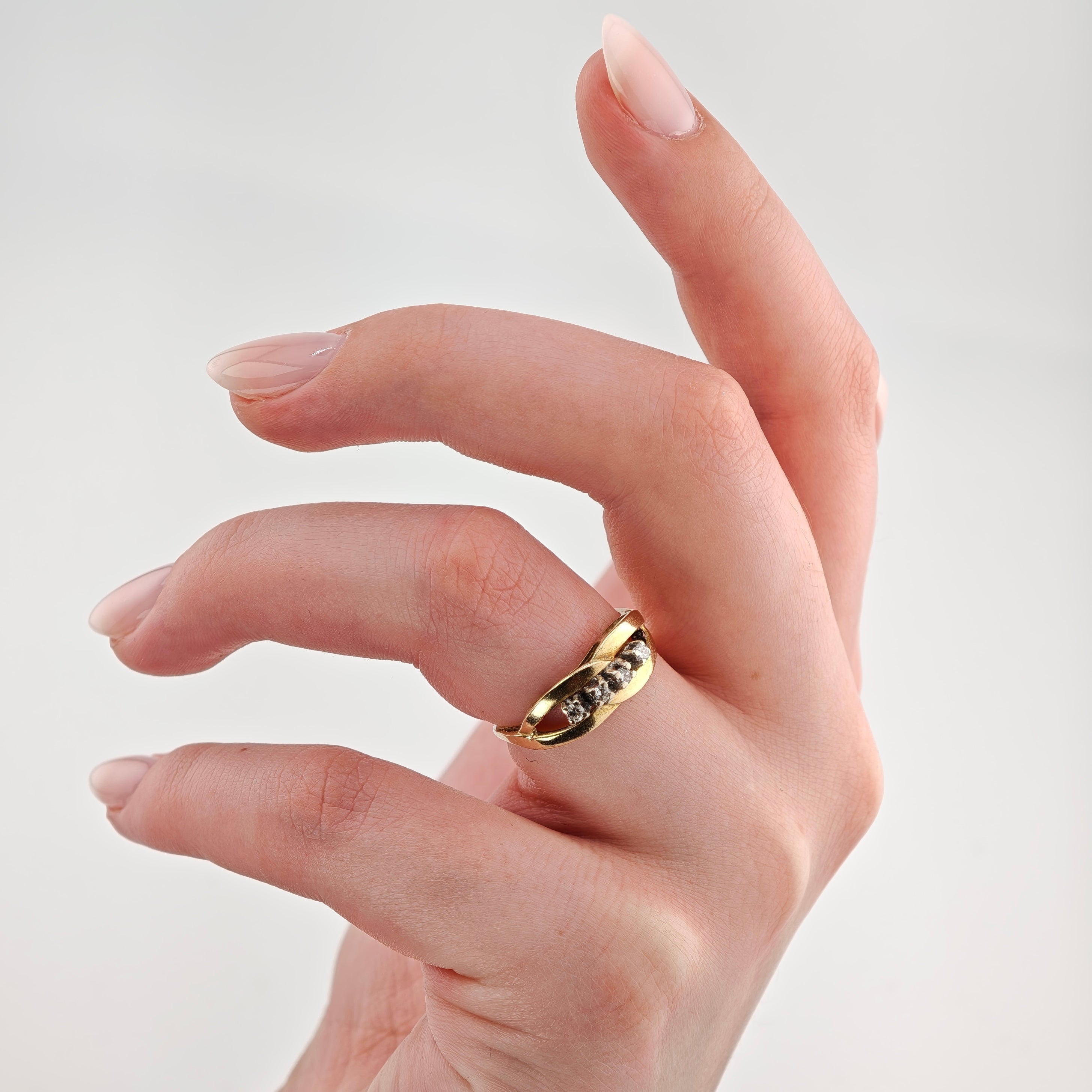 Elegante Hand mit glänzenden Nägeln und goldenen Ring mit Edelsteinen vor grauem Hintergrund