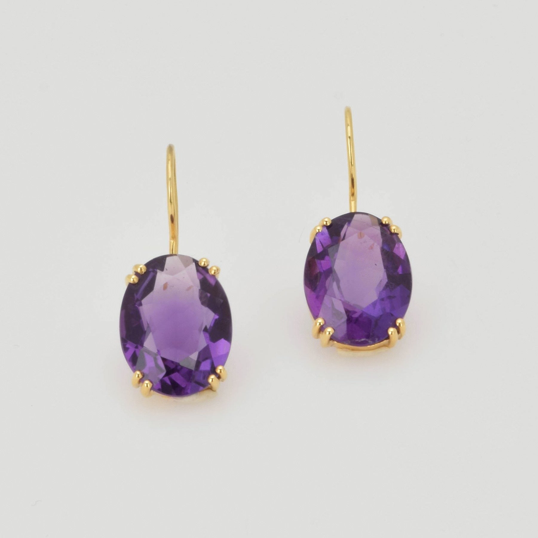 Paar elegante Ohrringe mit ovalen Amethysten in Goldfassung, goldene Haken für durchbohrte Ohren.