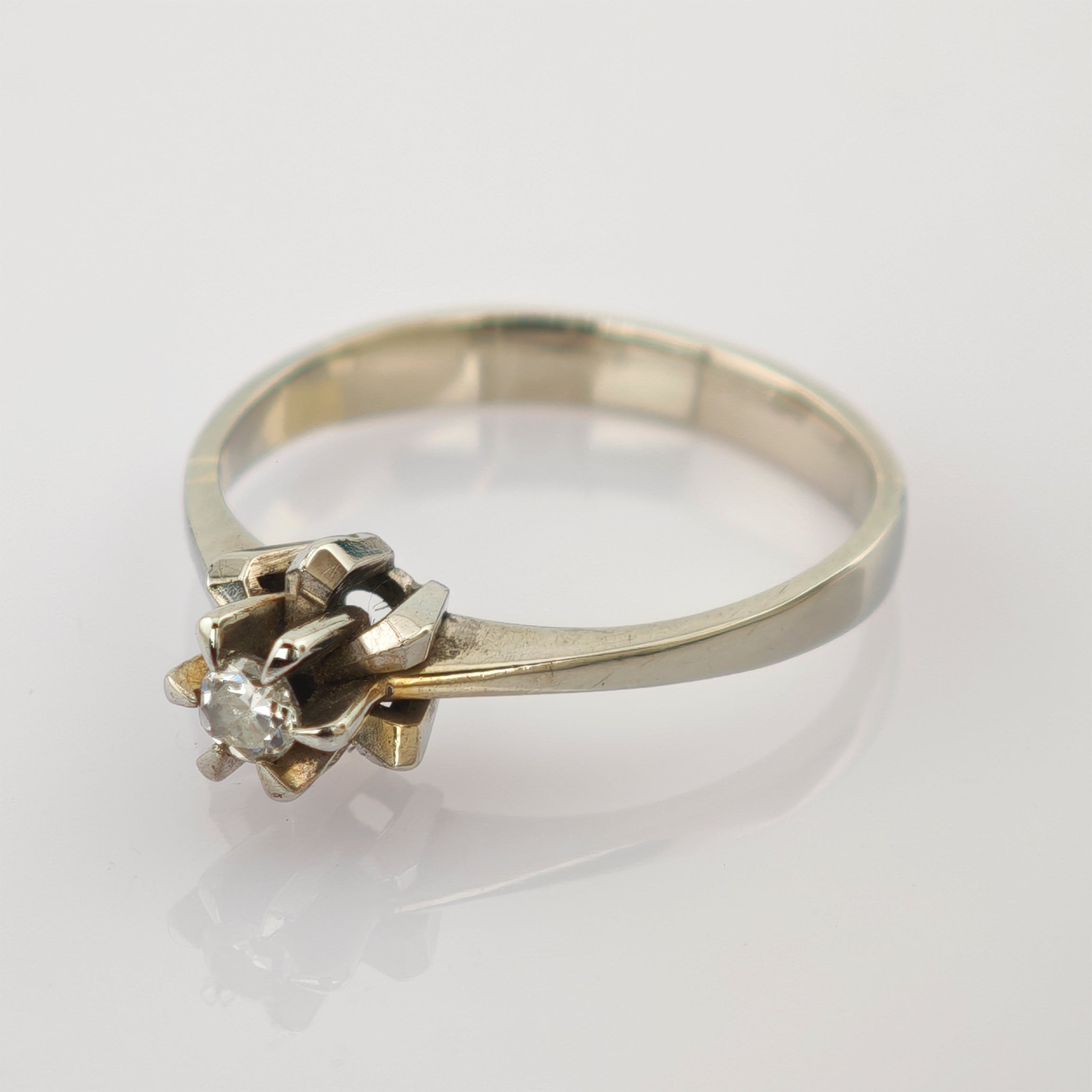 Eleganter Goldring mit einzelner funkelnder Diamantfassung und sechszackiger Krone auf weißem Hintergrund