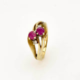 Eleganter Goldring mit zwei runden pinken Edelsteinen und kleinen klaren Steinen auf kunstvoll gewellten Bändern.