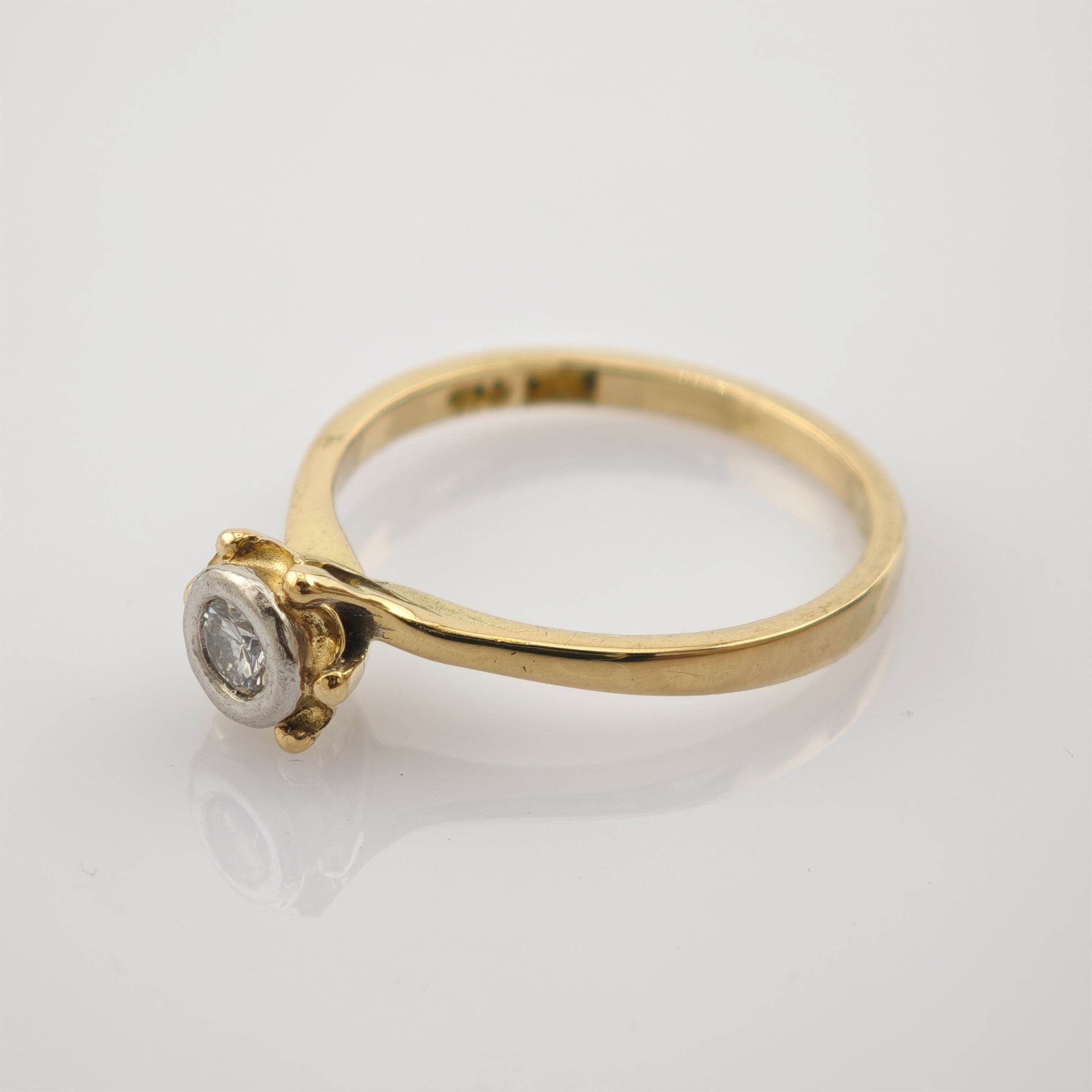 Eleganter Goldring mit schlankem Band und rundem Diamanten in Silberfassung mit Punze 750.