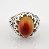 Eleganter Silberring mit ovalem rot-orangefarbenem Stein und filigranem Blatt- und Rankenmuster.