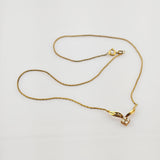 Feine Goldkette mit Anhänger aus flügelförmigen Goldelementen und Diamanten auf weißem Hintergrund.