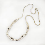 Feine Silberkette mit kleinen schwarzen Edelsteinen und sichtbarem Verschluss auf weißem Hintergrund.