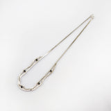 Feine silberne Halskette mit wellenförmiger Gliederung und sechs schwarzen Perlen auf weißem Hintergrund.