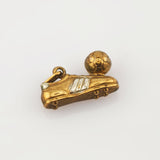 Goldener Anhänger in Fußballschuhform mit silbernen Streifen und kleinem Fußball mit hexagonalen Mustern.