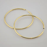 Zwei große, goldene Creolen auf weißem Untergrund