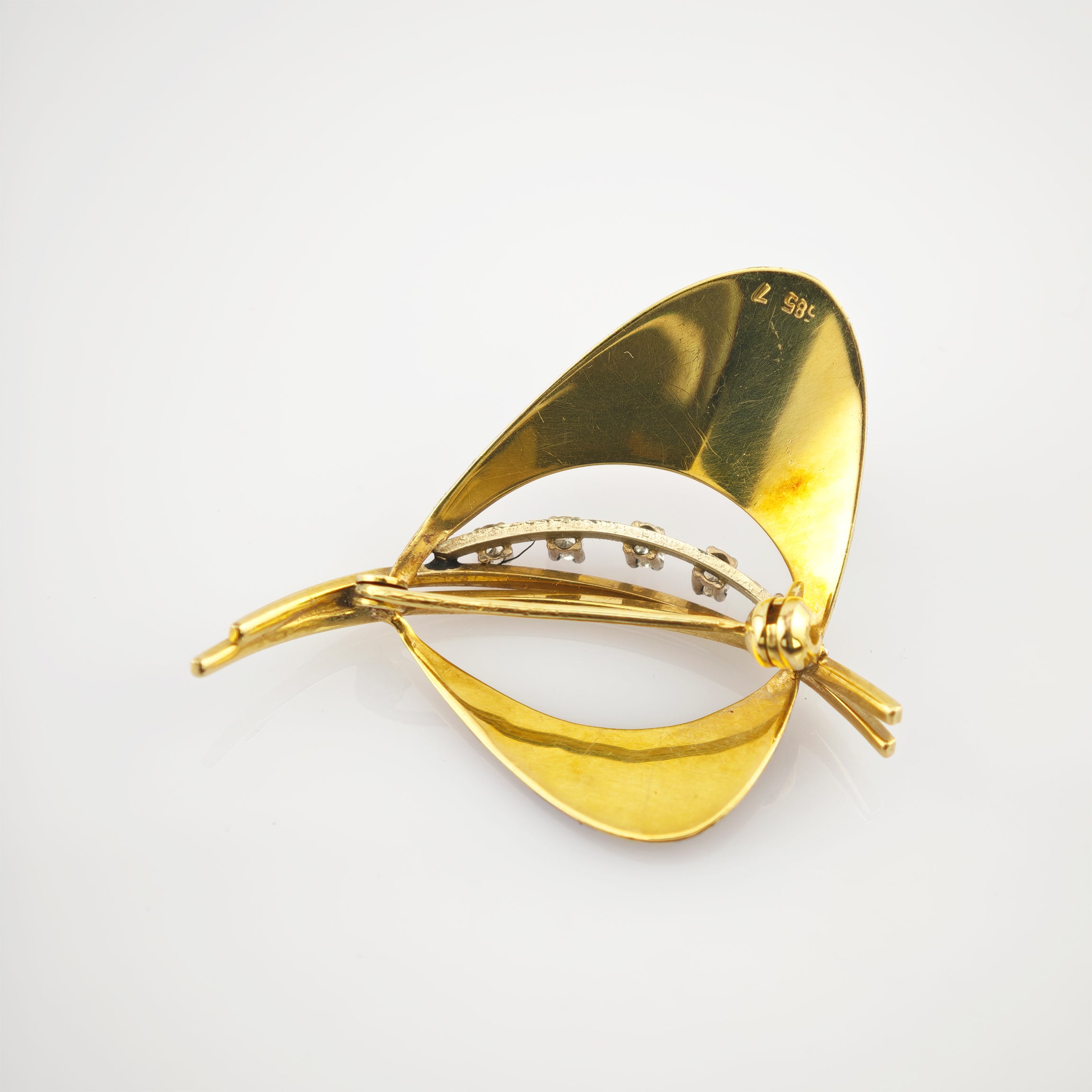 Goldene Brosche mit zwei geschwungenen Flügeln und zentraler Stange mit Edelsteinen.