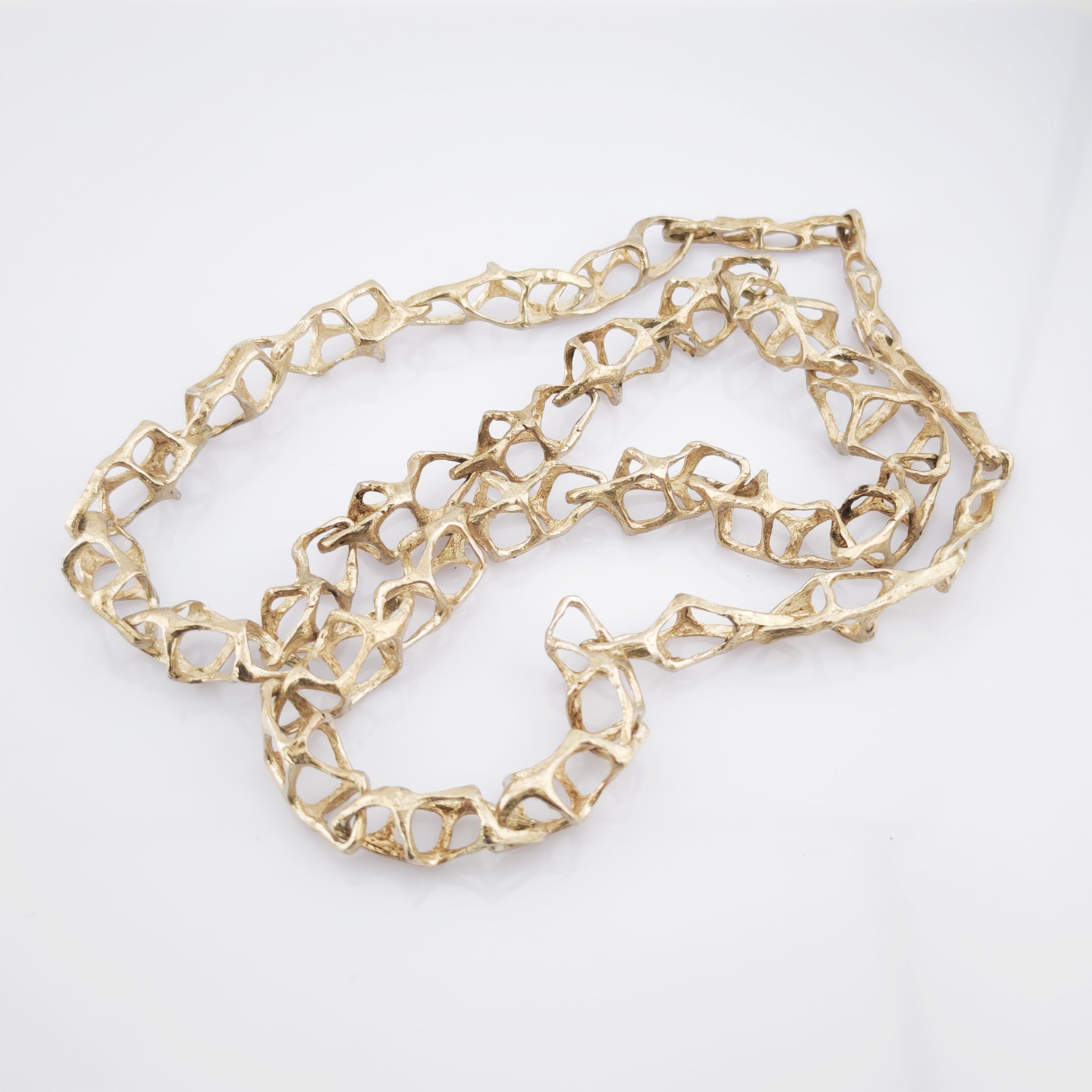 Goldene Halskette mit unregelmäßig geformten geometrischen Gliedern auf weißem Hintergrund