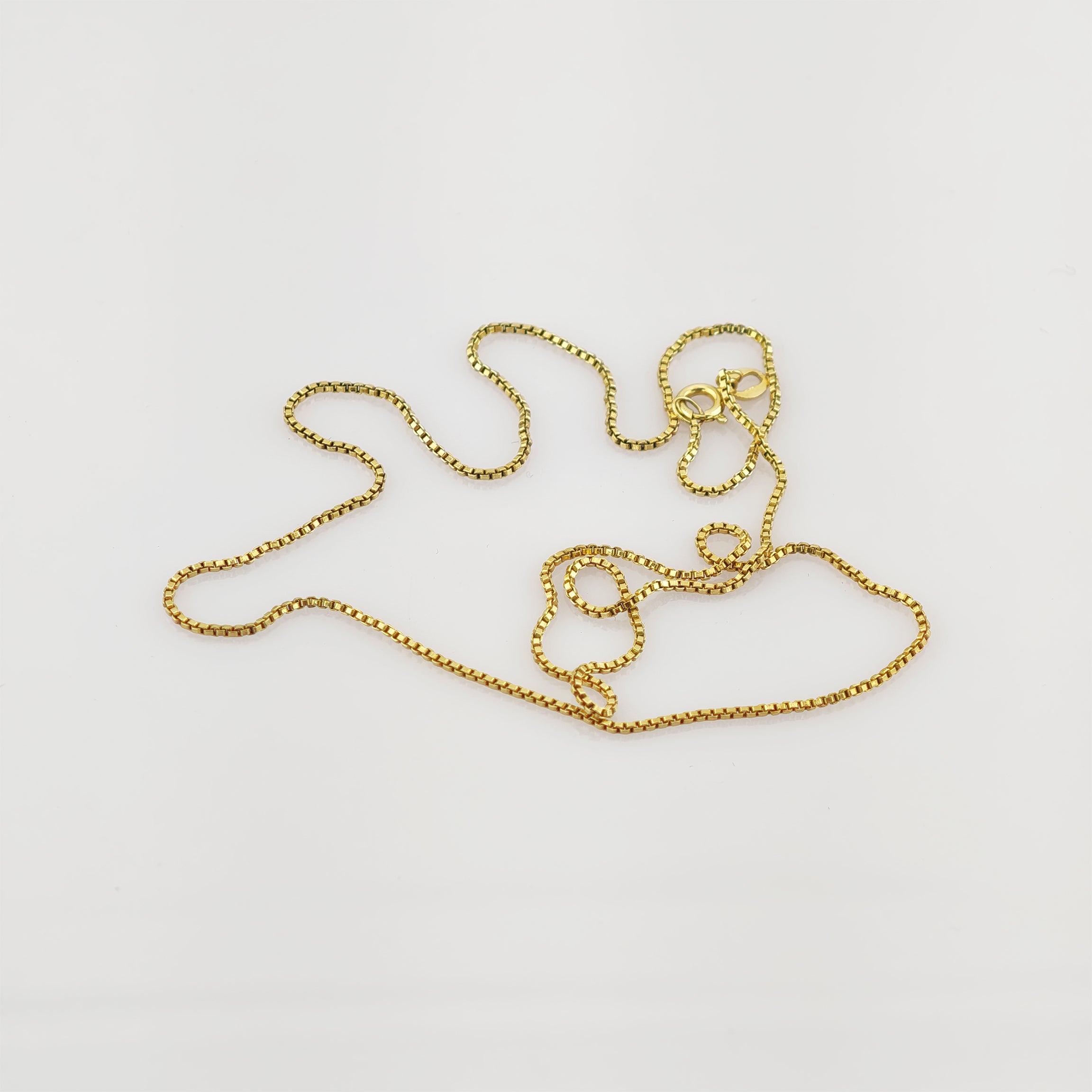 Goldene Halskette mit Kastenglied-Design auf weißem Hintergrund