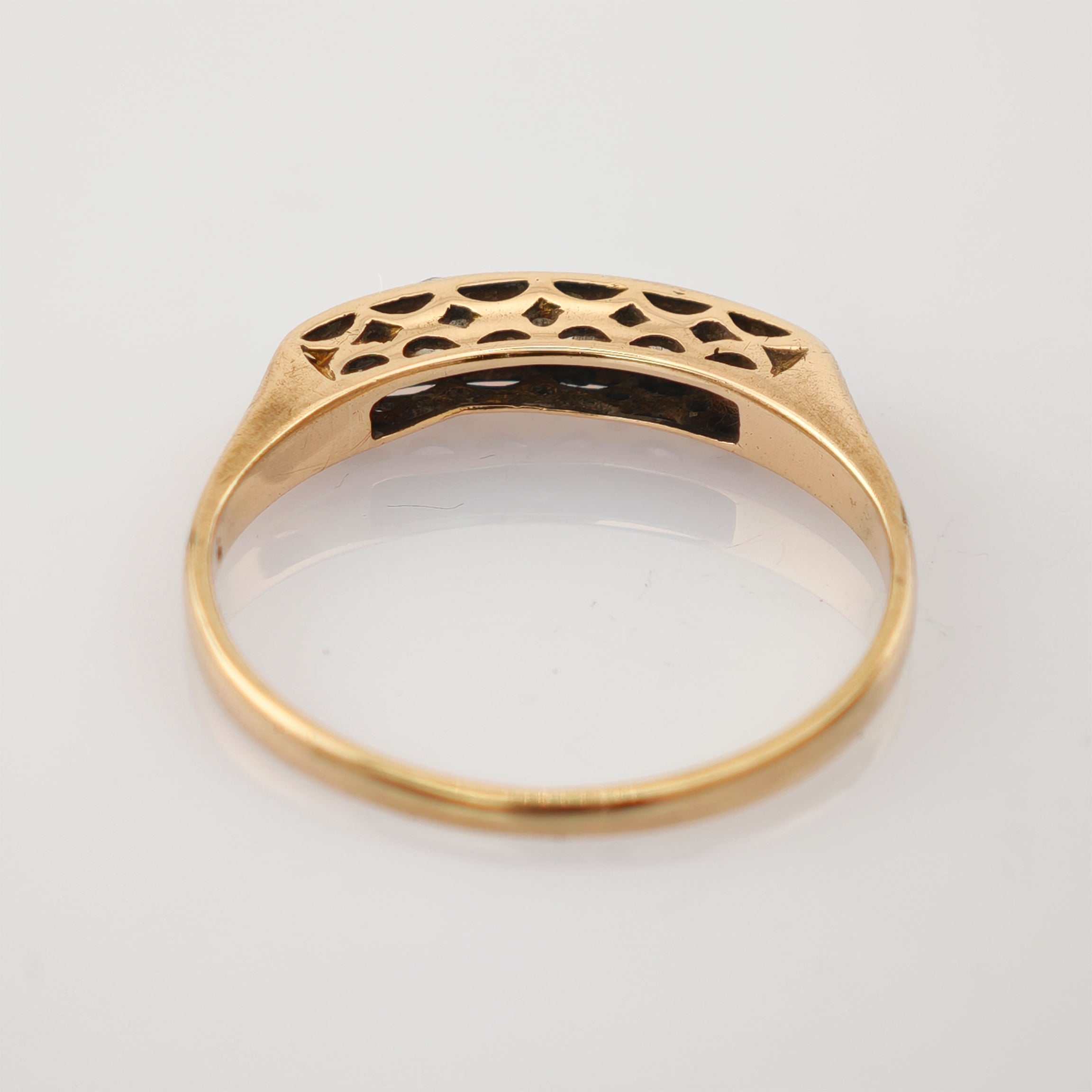 Goldener Ring mit filigranen Ausschnitten und elegantem Hohlraummuster auf hellem Hintergrund