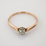 Goldener Ring mit klarem Einzelstein in Drahtfassung auf schlichtem Hintergrund