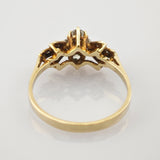 Goldener Ring mit kronenförmigem Fassungsdesign und mehreren Steinen, von unten aufgenommen.