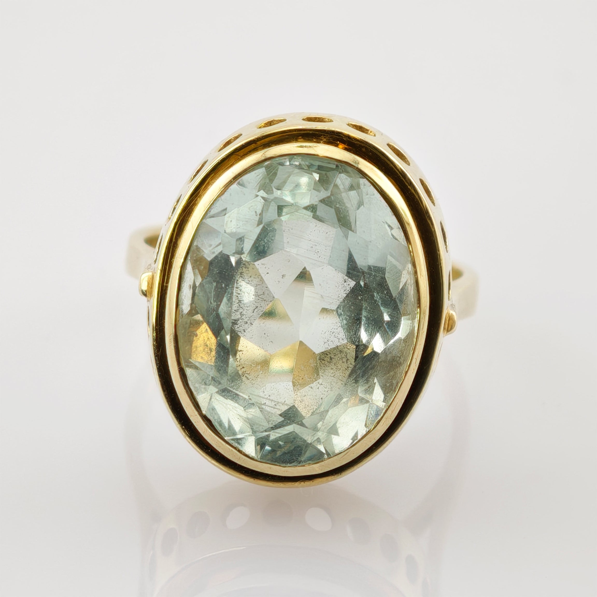 Goldener Ring mit großem ovalem facettiertem hellgrünem Schmuckstein und dekorativen Rundausschnitten