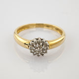 Goldener Ring mit rundem Cluster aus kleinen Diamanten, silberne Fassung, glänzende weiße Oberfläche.