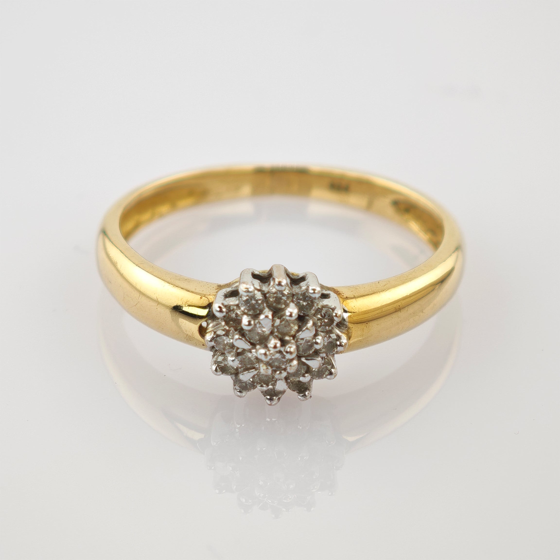 Goldener Ring mit rundem Cluster aus kleinen Diamanten, silberne Fassung, glänzende weiße Oberfläche.
