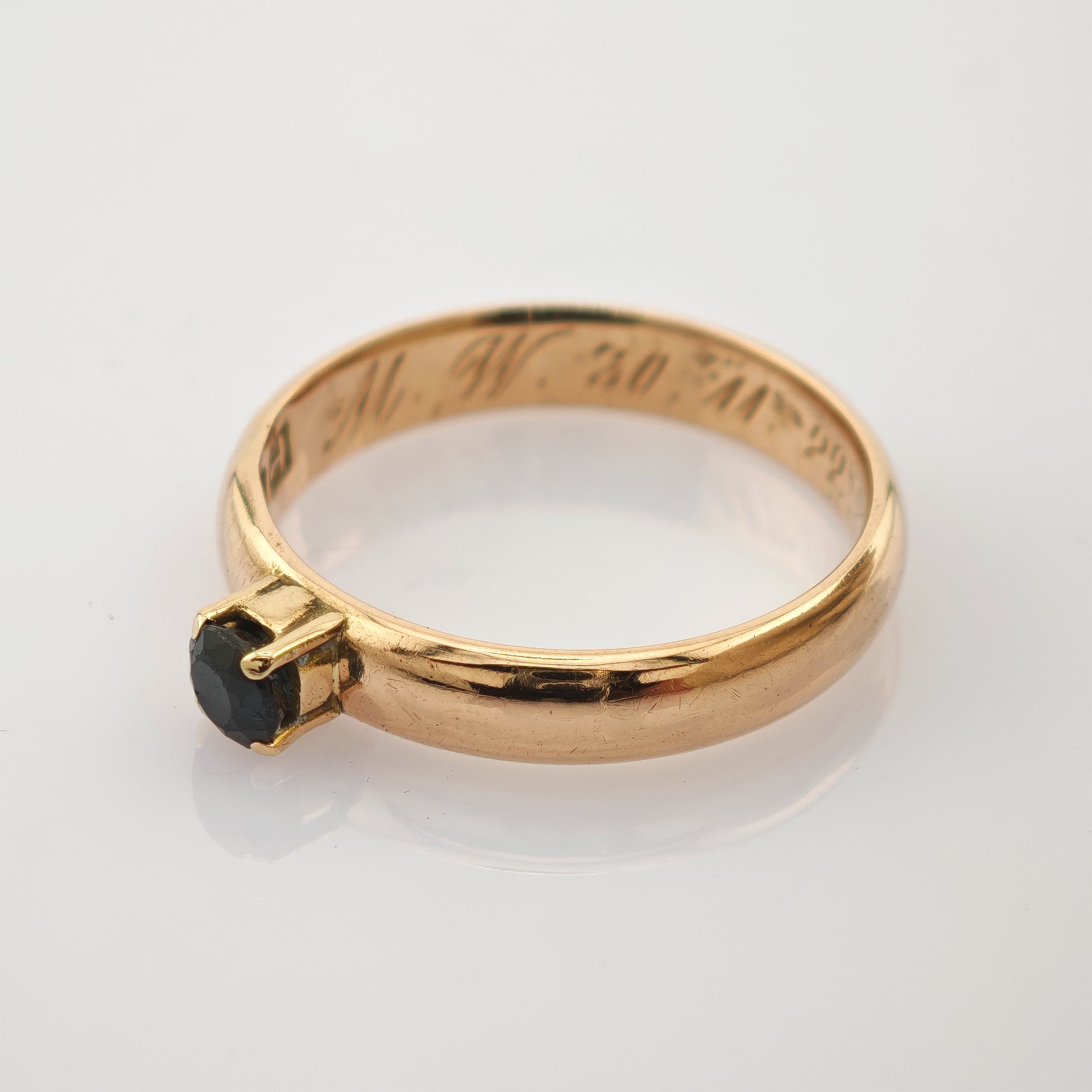 Goldener Ring mit schwarzem Edelstein und gravierter Inschrift M. W. 30. XI. 22 auf dem Innenband.