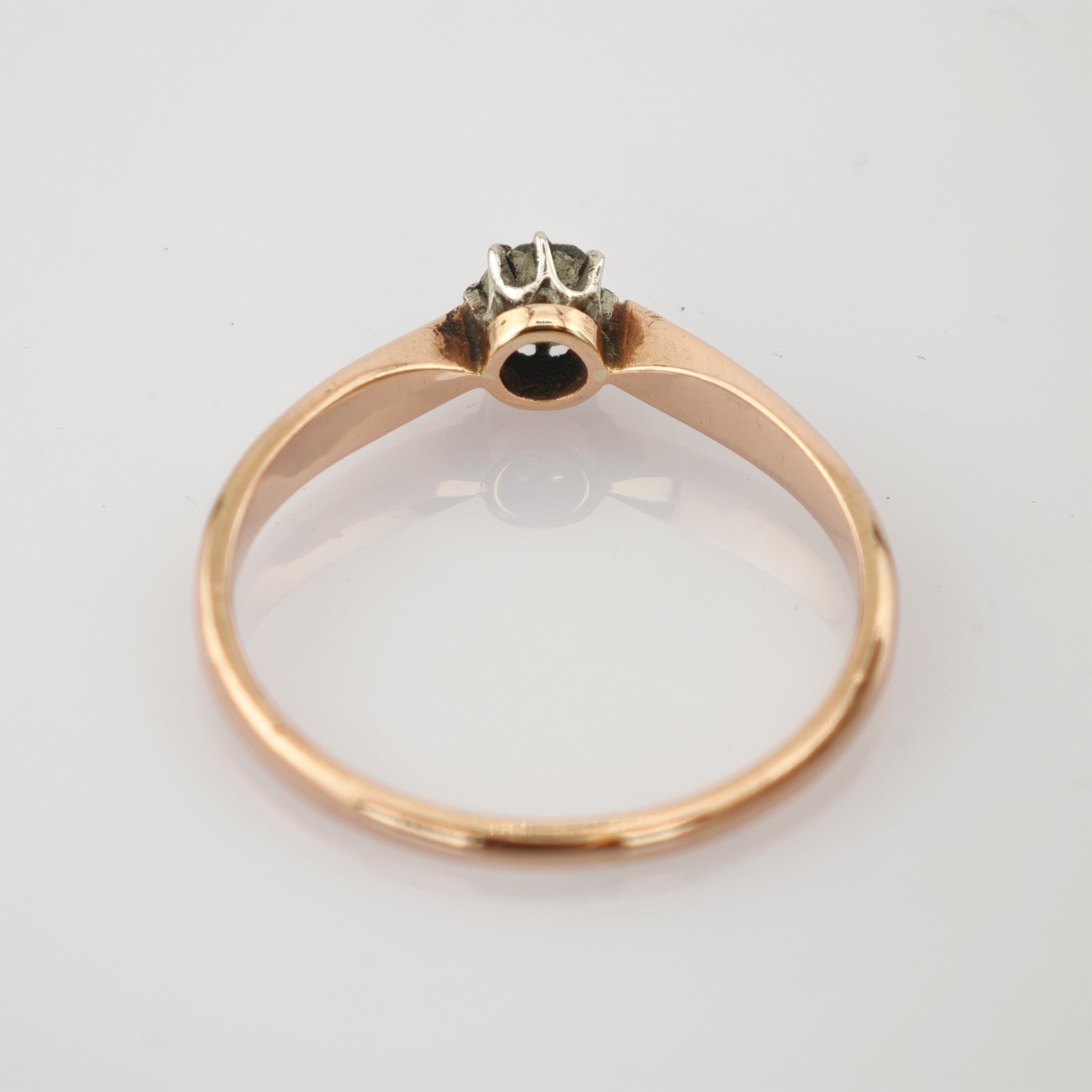 Seitliche Ansicht eines goldenen Rings mit glatter Oberfläche und kleiner Fassung ohne Edelstein.