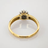 Goldener Ring mit vier weißen Steinen auf polierter Oberfläche.