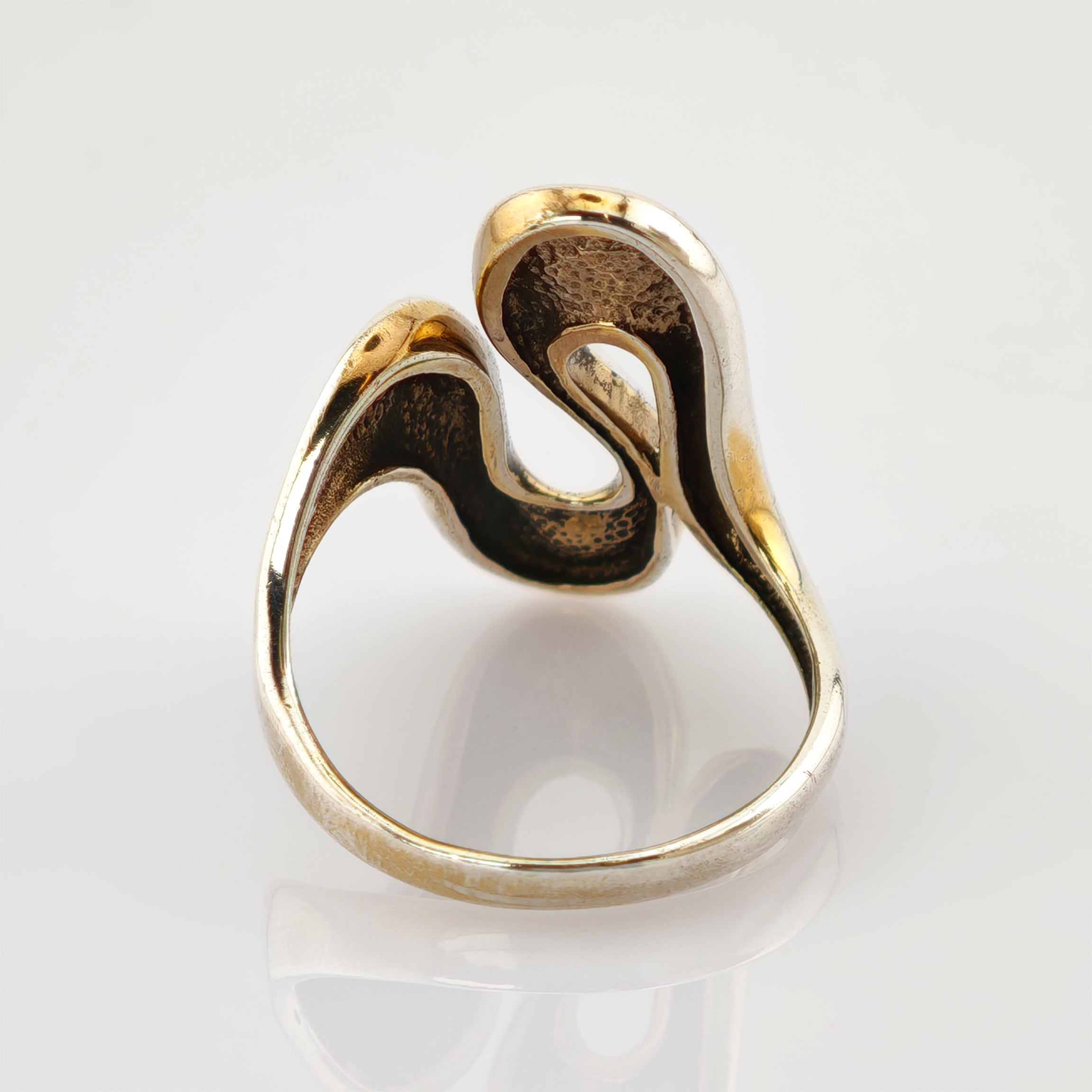 Goldener Ring mit elegantem wellenförmigem Design und gehämmerter Innenseite auf glänzend weißem Hintergrund.