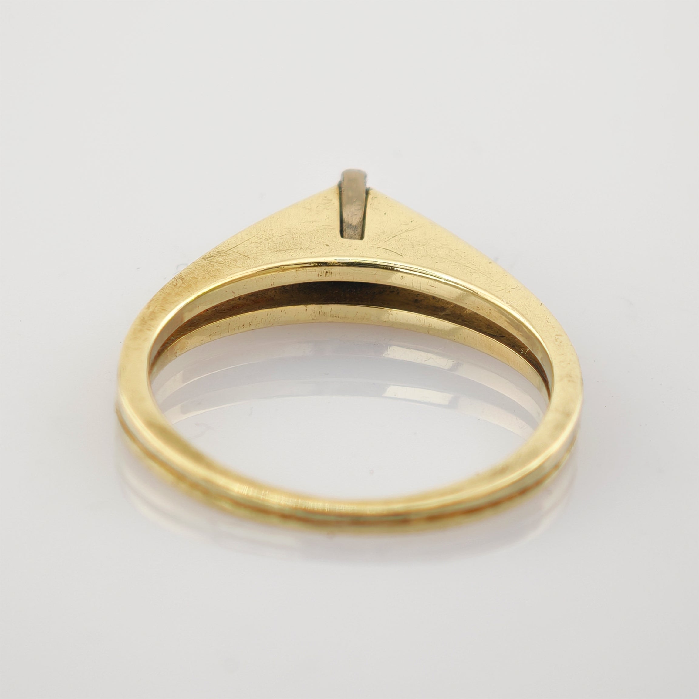 Goldener Vintage-Ring mit flacher, dreieckiger Oberfläche und kleinem, erhöhtem Detail auf weißem Untergrund.