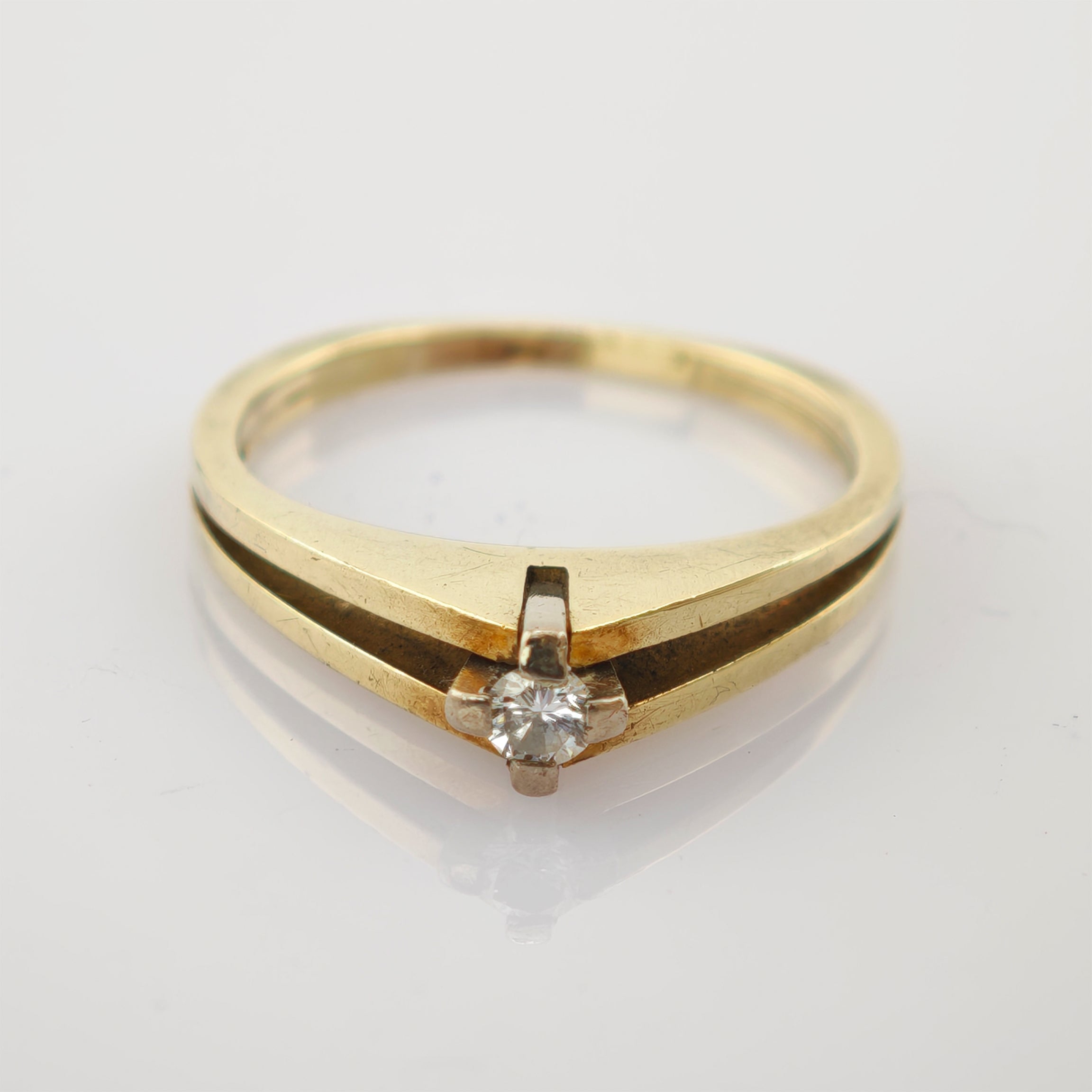 Goldener Vintage-Ring mit rundem klaren Edelstein in silberner Fassung auf weißer Fläche