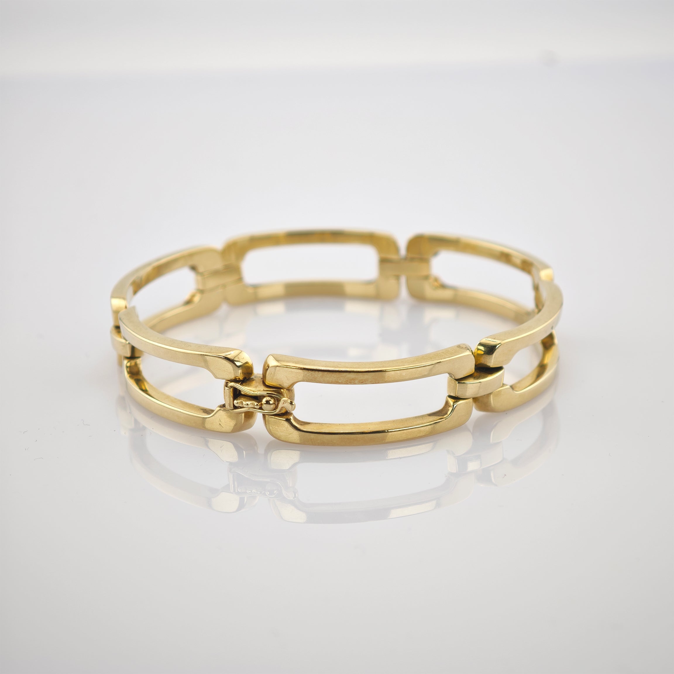Goldenes Armband mit rechteckigen Gliedern auf weißer Fläche