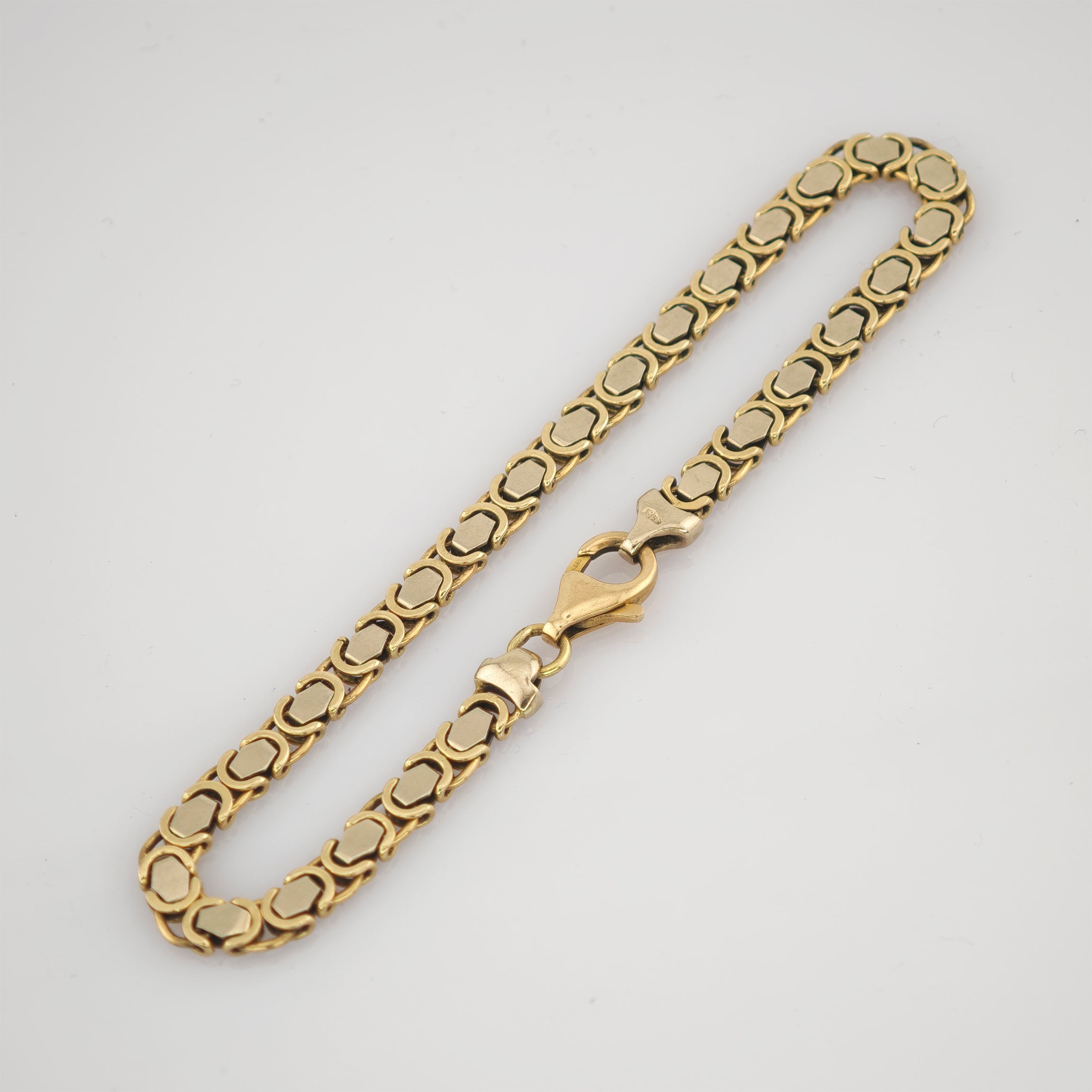 Goldenes Kettenarmband mit rechteckigen Gliedern und polierter Oberfläche auf weißem Hintergrund.