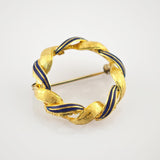 Goldfarbene runde Brosche mit verschlungenem Design aus Gold und marineblauem Email.
