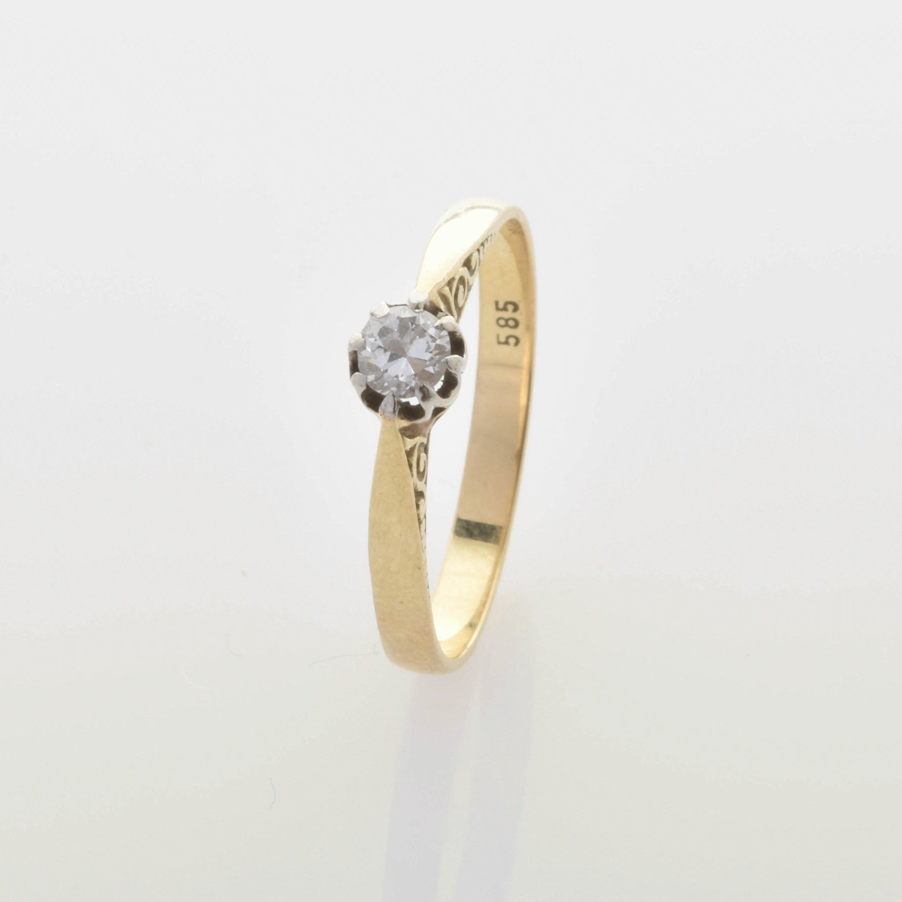 Goldring mit zierlichen Gravuren und rundem klarem Stein, innen mit 585-Goldstempel.