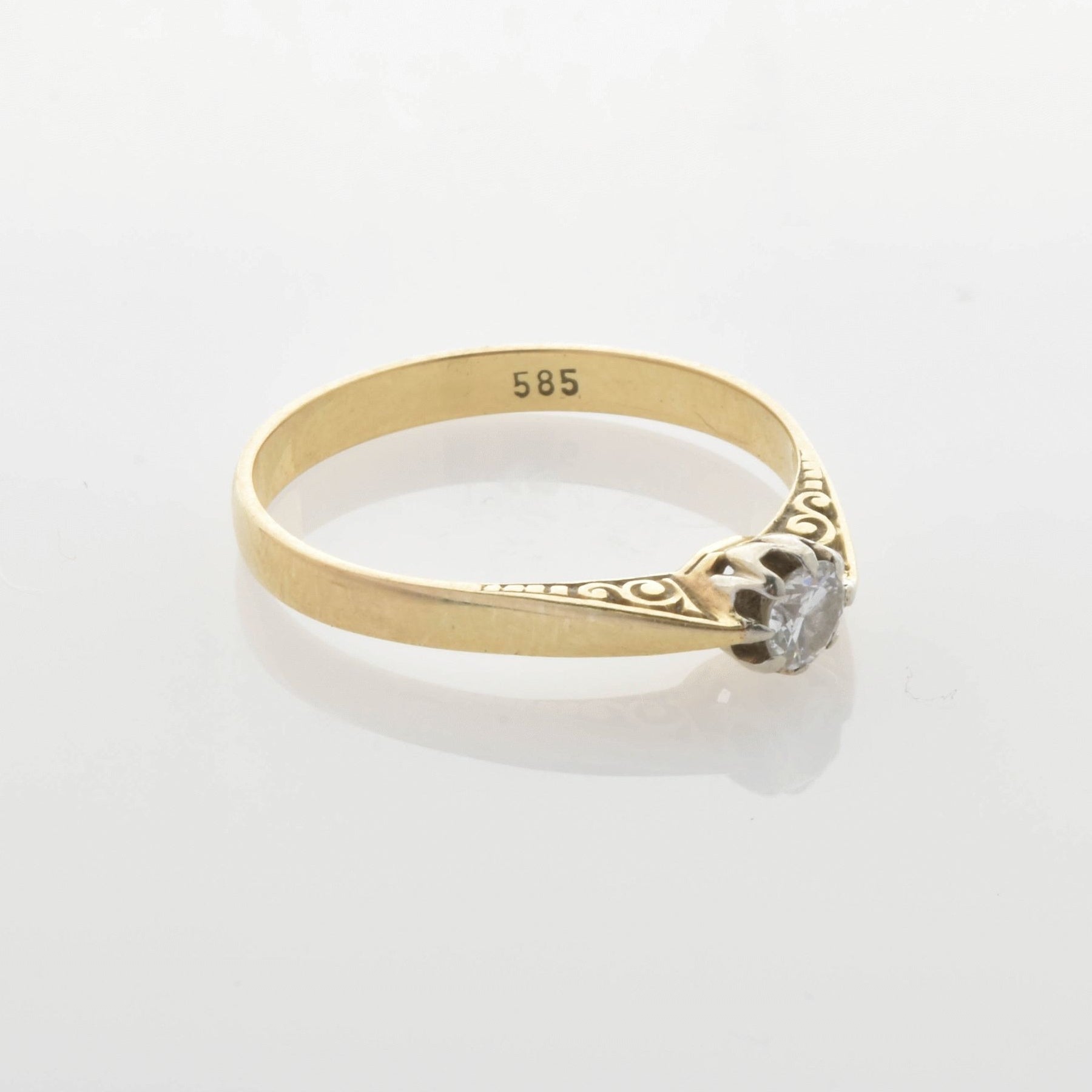 Goldring mit zierlichen Gravuren und rundem klarem Stein, innen mit 585-Goldstempel.