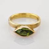 Goldring mit einem Marquise-Schliff grünen Edelstein auf weißem Untergrund