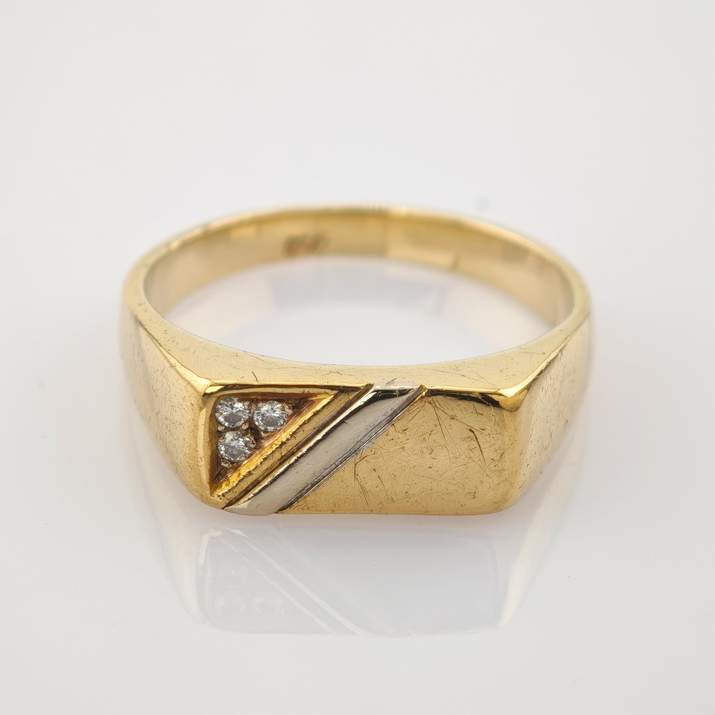 Goldring mit rechteckiger Fläche, drei klaren Steinen in Dreiecksfassung und silbernem Streifen, gestempelt 375.