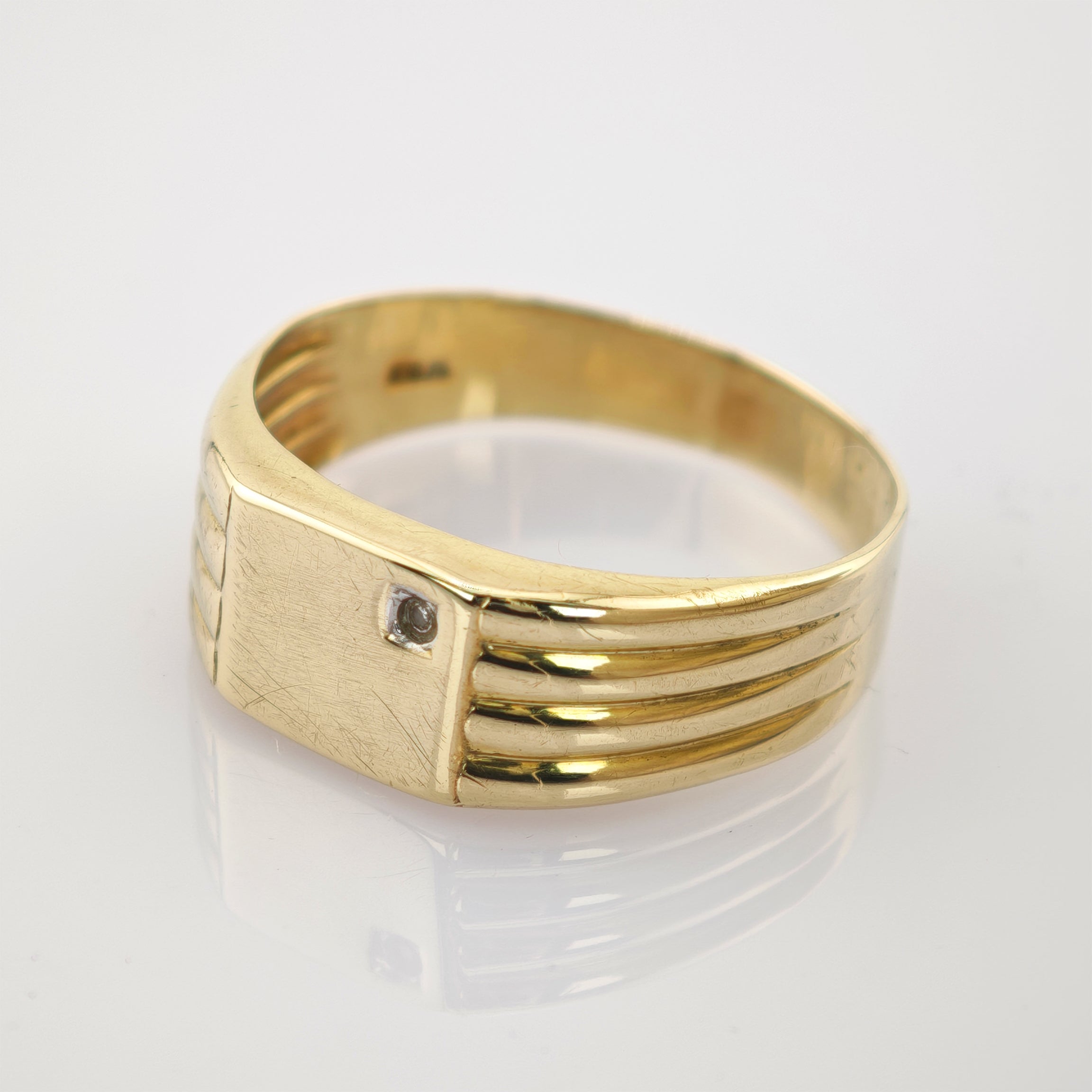 Goldring mit rechteckiger Oberseite und kleinem Eckstein, mit parallelen Linien an den Seiten