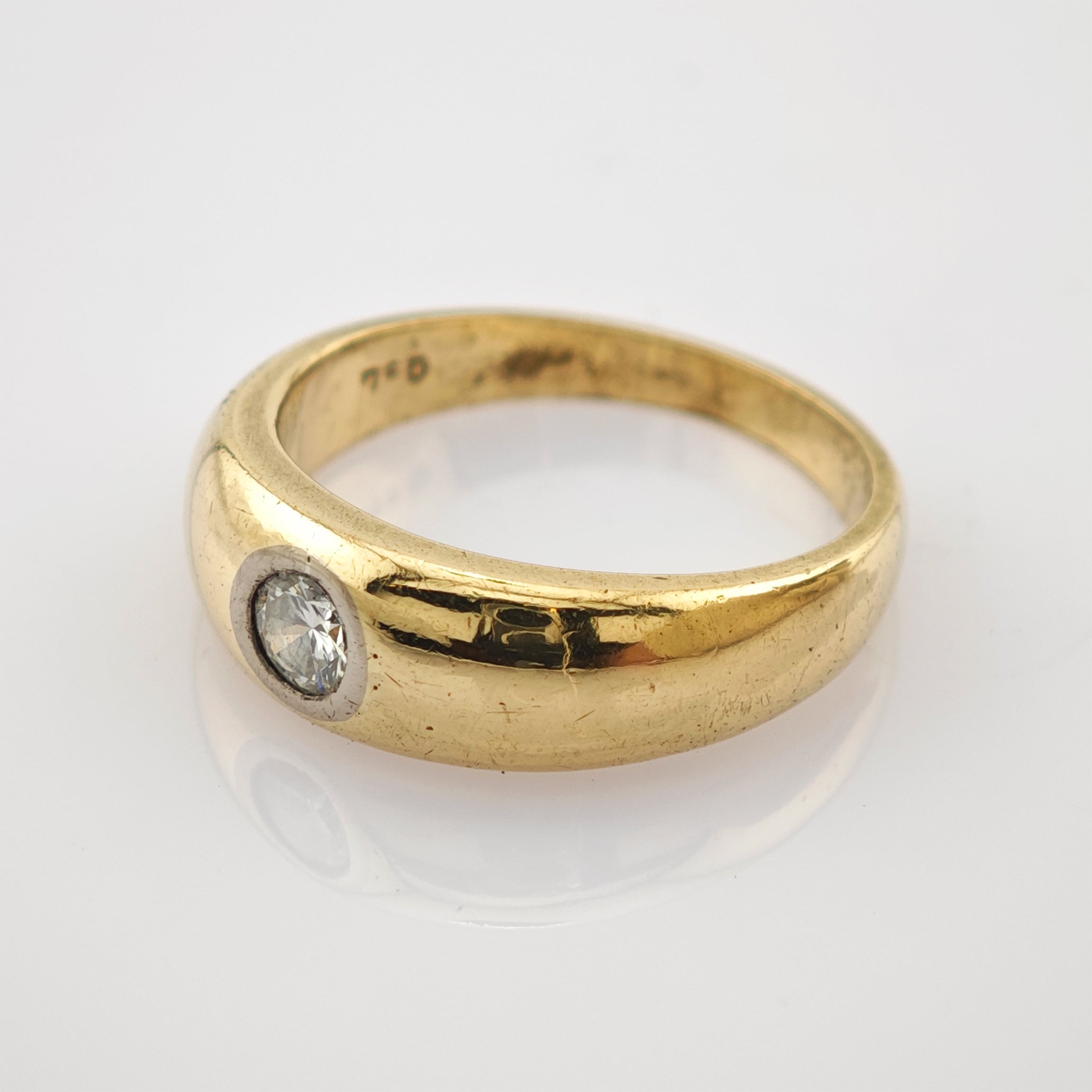 Goldring mit rundem Diamant in silberner Fassung und eingravierter 750-Punze.