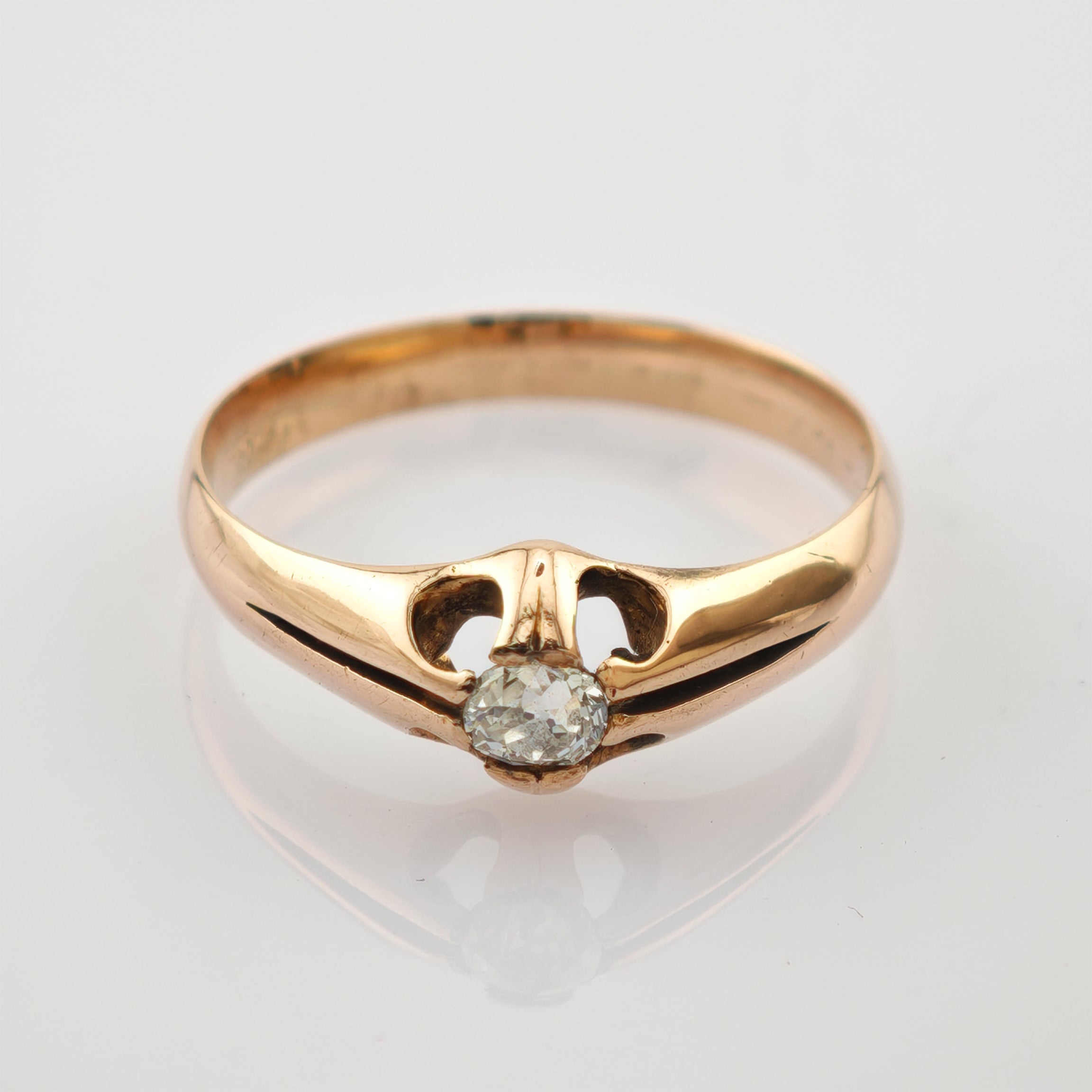 Goldring mit rundem klaren Stein in offener Fassung vor weißem Hintergrund
