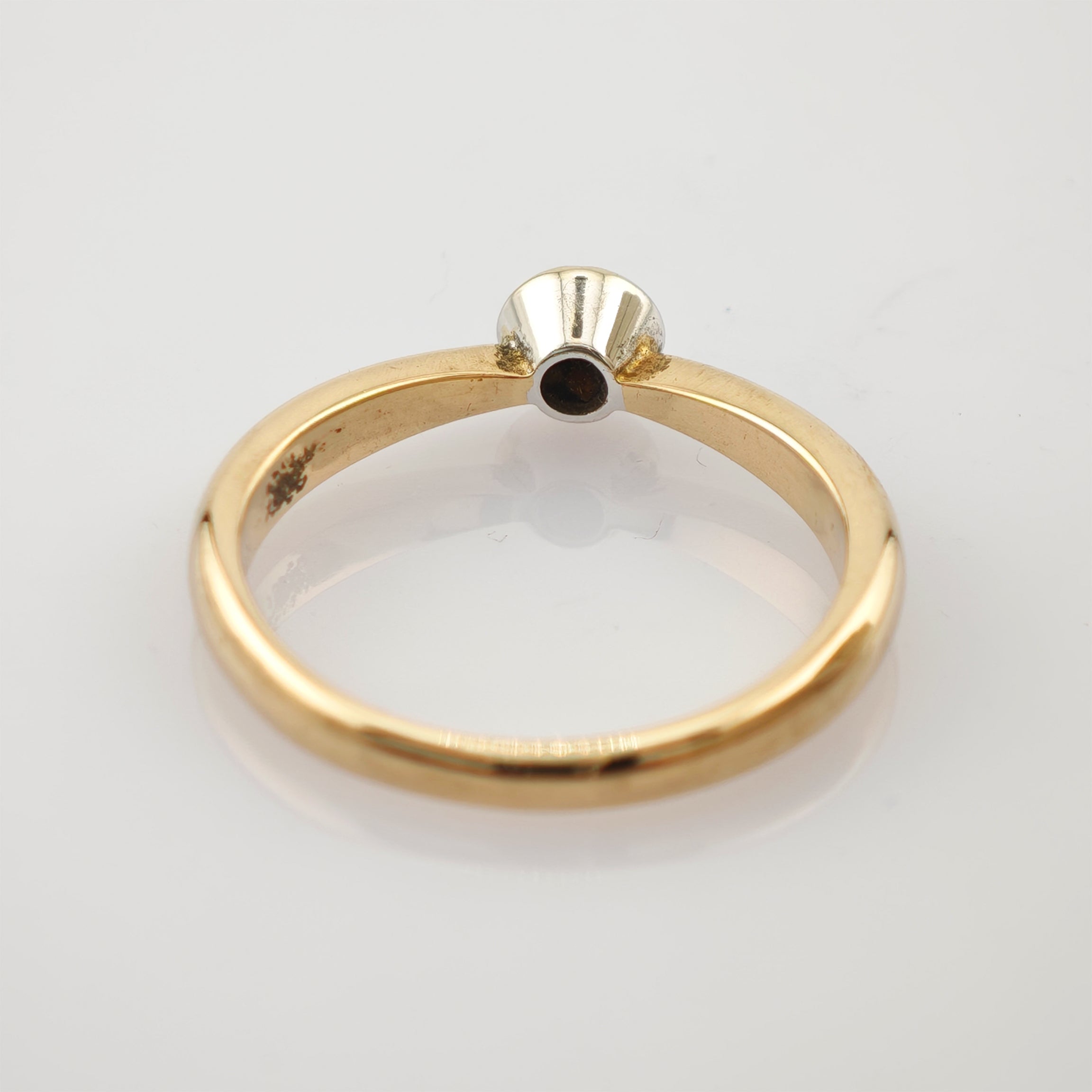 Goldring mit Weißgoldfassung und dunklem mittigem Loch, minimalistisches und elegantes Design.