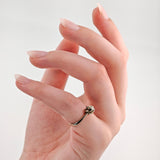 Hände mit gepflegten, mandelförmigen Nägeln in Zartrosa und silbernem Ring mit floralem Design und Diamant.