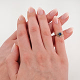 Zwei ineinandergreifende Hände mit silbernem Ring und blauem Edelstein.